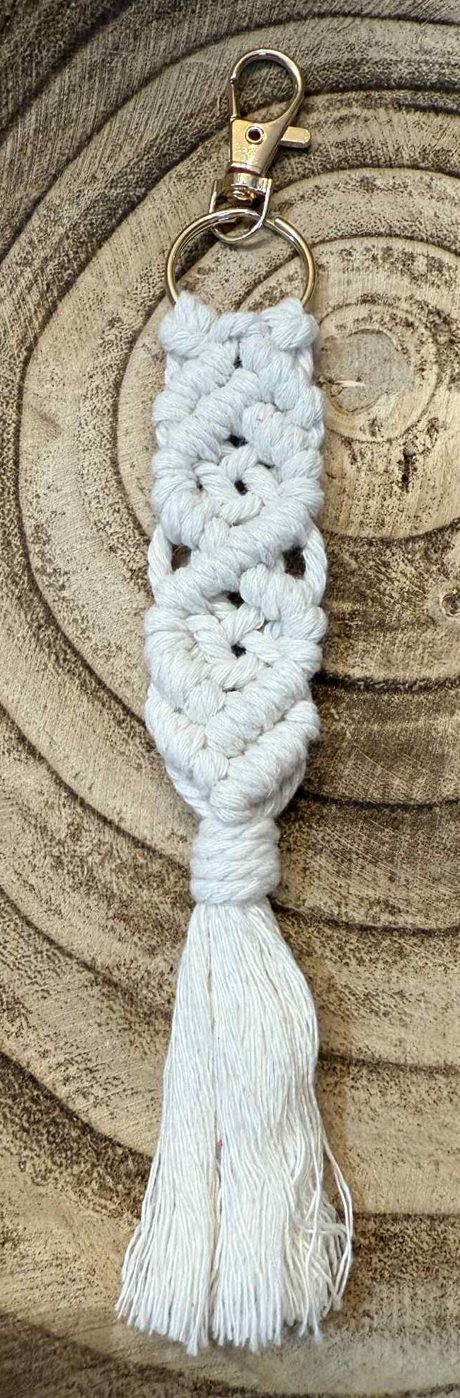 White macrame keychain with tassel on a wooden surface