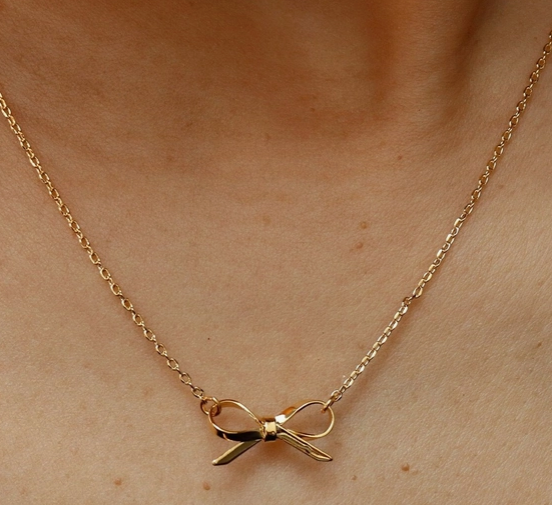 Gold bow necklace on a person's neck