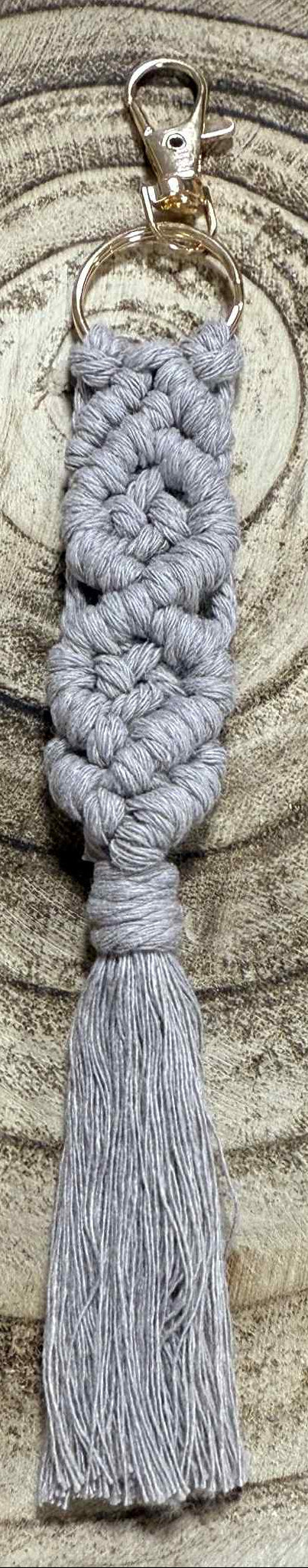 Gray braided keychain with tassel on a wooden surface