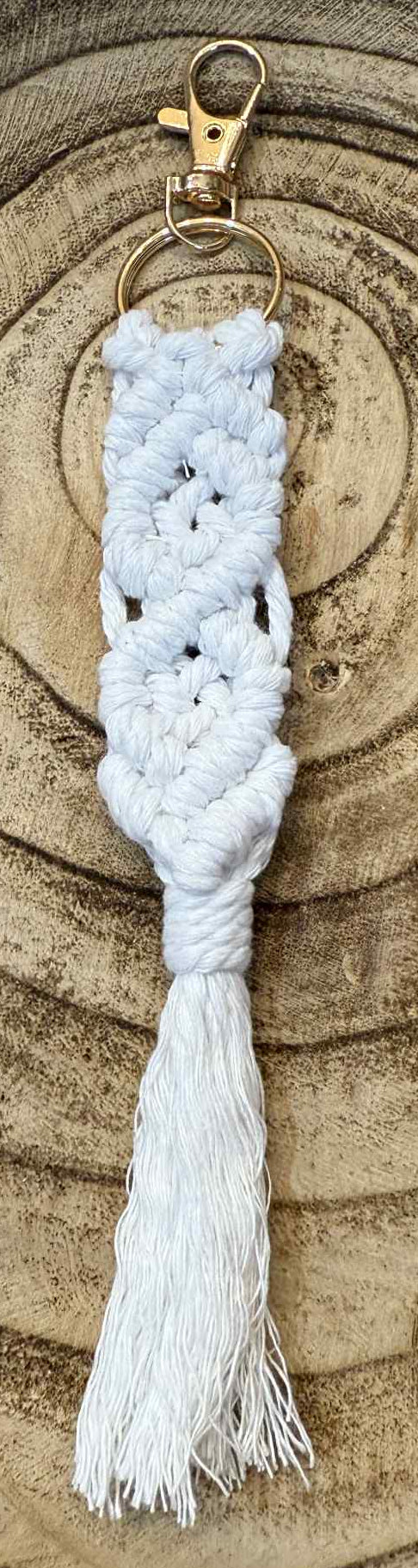 White macrame keychain with tassel on a wooden surface
